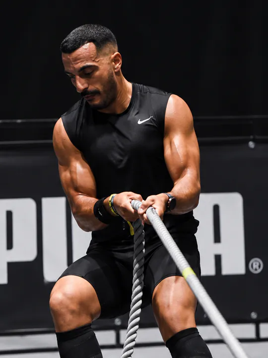 Gros plan sur le coach qui tire la corde du sled pull pendant une course HYROX